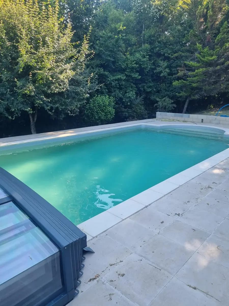 Piscine à eau vert-émeraude trouble avec abri coulissant — eau voilée typique d'un déséquilibre chimique